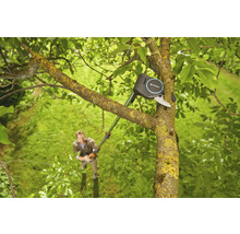 Eine Gardena Astschere im Einsatz an einem Baum, während eine Person im Hintergrund steht.