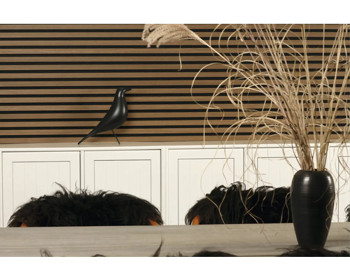 Dekoratives Interieur mit Wandpaneelen in Holzoptik, einer Vogelstatue und einer Vase mit Dekoration