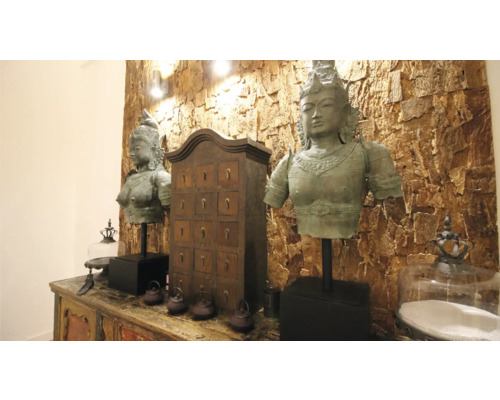 Dekoratives Arrangement mit zwei Buddha-Statuen, einem Apothekerschrank und dekorativen Accessoires auf einem verzierten Sideboard.