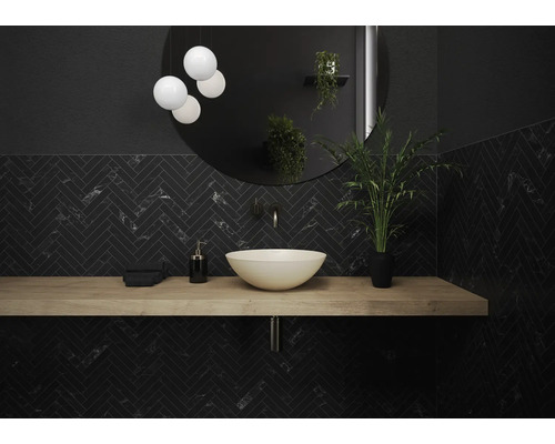 Modernes Badezimmer mit Waschbecken, Spiegel, Beleuchtung und dunklen Fliesen im Fischgrätmuster.