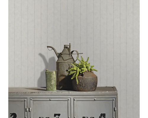 Dekorative Metallelemente und eine Zimmerpflanze auf einem Metallschrank vor einer gestreiften Wand