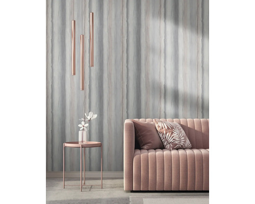 Wohnzimmer mit Sofa, Kissen, Beistelltisch, Blumenvase und Pendelleuchten vor einer gestreiften Tapete