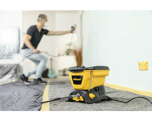 Farbsprühsystem mit Mann beim Sprühen einer Wand im Innenbereich