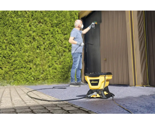 Mann lackiert Garagentor mit Farbsprühsystem von Wagner