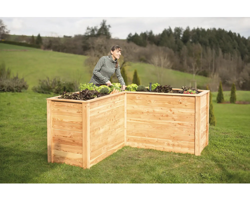 Hochbeet aus Holz im Garten mit Frau bei der Gartenarbeit