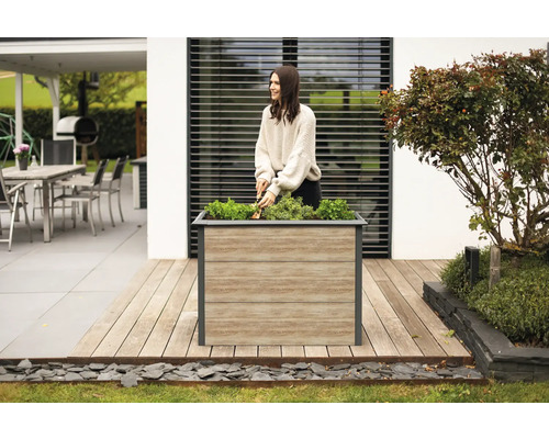 Frau arbeitet im Garten mit einem Pflanzkasten auf einer Terrasse