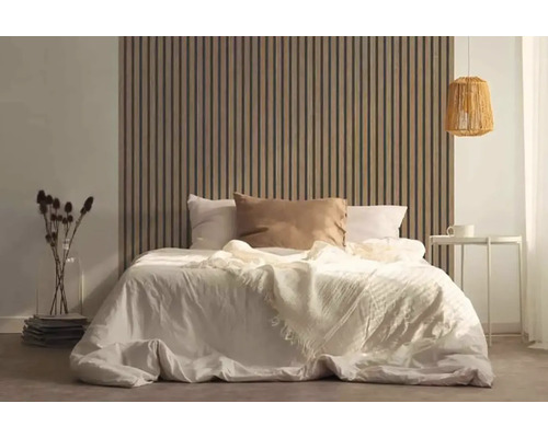 Schlafzimmer mit Bett vor einer Wandverkleidung aus Holzlatten, Nachttisch und Lampe