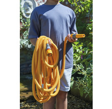 Eine Person hält einen flexiblen Gartenschlauch mit Sprühkopf und Anschlussstück.