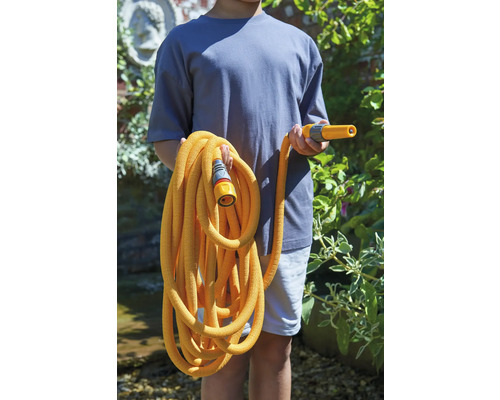 Eine Person hält einen flexiblen Gartenschlauch mit Sprühkopf und Anschlussstück.