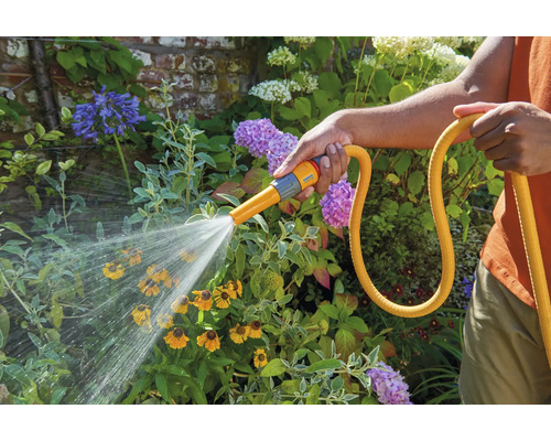 Bewässerung von Blumen mit einem Gartenschlauch und Sprühdüse