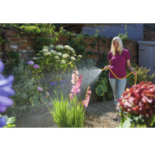 Frau bewässert Garten mit Gartenschlauch
