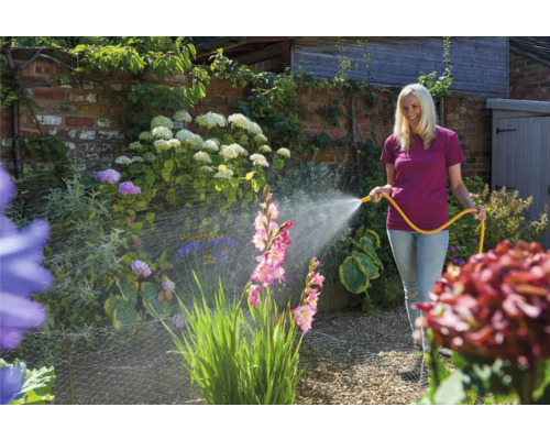 Frau bewässert Garten mit Gartenschlauch