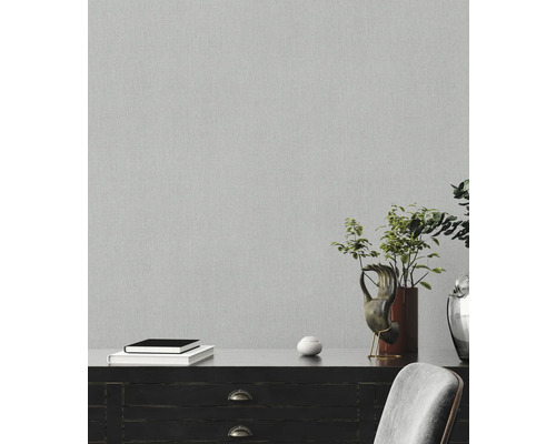 Nahaufnahme einer grauen Vliestapete mit feiner Struktur an einer Wand.