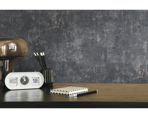 Dekoratives Interieur mit Lampe, Tischuhr, Notizblock und Bleistiften auf einem Tisch vor einer strukturierten Wand