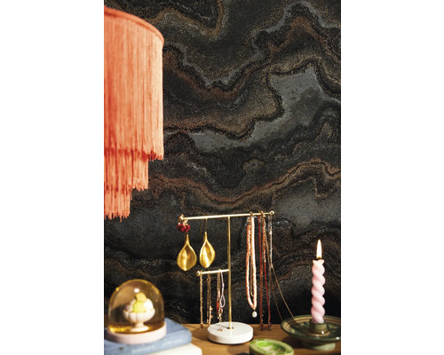 Raumansicht mit dunkler Marmortapete, Stehlampe, Schmuckständer und Kerze