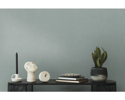 Dekorative Gegenstände wie Kerze, Skulptur, Uhr, Bücher und Topfpflanze auf einem Tisch