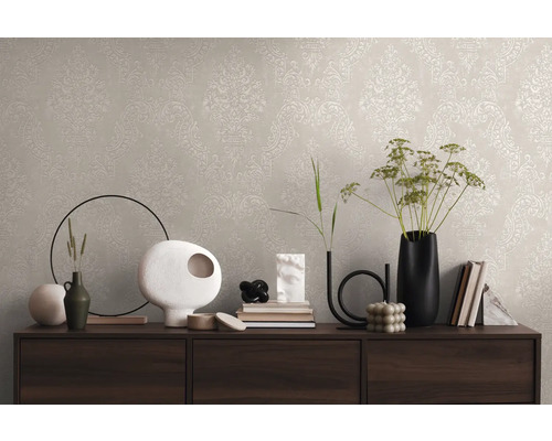 Wandgestaltung mit beiger Tapete und klassischem Muster auf einer Kommode mit dekorativen Vasen und Büchern
