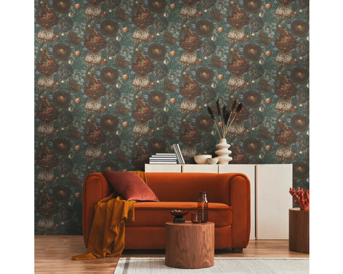 Ein Wohnzimmer mit einer floral gemusterten Tapete, einem Sofa, einem Beistelltisch und einer Kommode.