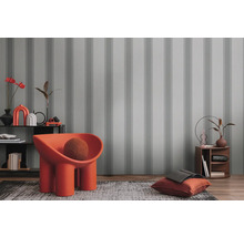 Dekoratives Interieur mit gestreifter Tapete, Sessel und Wohnaccessoires
