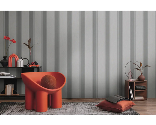 Dekoratives Interieur mit gestreifter Tapete, Sessel und Wohnaccessoires