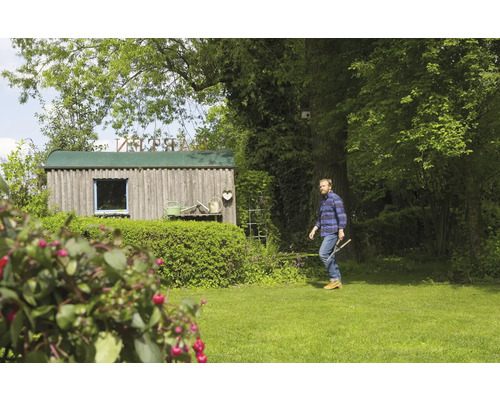 Gartenszene mit Gartenlaube, Grünfläche und Mann mit Gartengerät