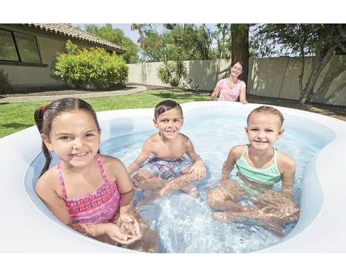 Kinder spielen in einem aufblasbaren Pool im Garten.