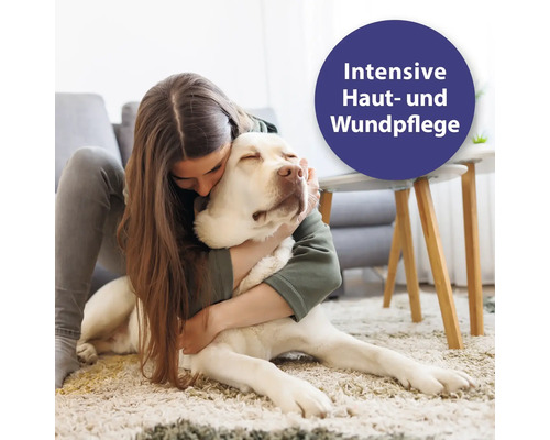 Eine Frau umarmt einen Labrador zur intensiven Haut- und Wundpflege.