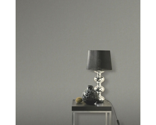Dekoratives Arrangement mit Lampe und Vase auf einem Tisch vor einer Wand