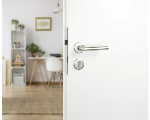 Geöffnete weiße Tür mit silberner Türklinke vor einem hellen Raum