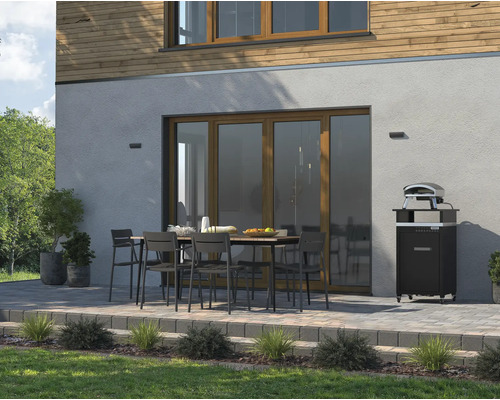 Außenbereich mit Esstisch, Stühlen und Pizzaofen vor einer Hauswand