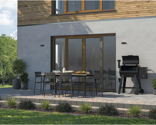 Außenbereich mit Esstisch, Stühlen und Grill neben dem Haus