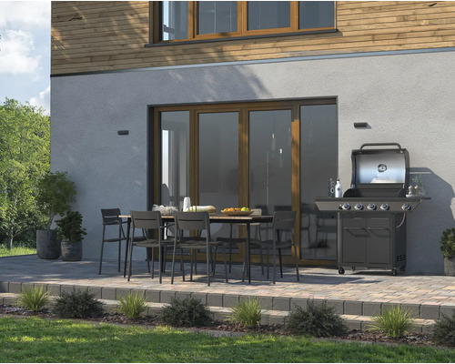 Terrasse mit Gartengrill, Esstisch und Stühlen vor einem Haus