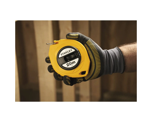Eine Hand mit Arbeitshandschuh hält ein gelbes 20 Meter langes Bandmaß der Marke Stanley.