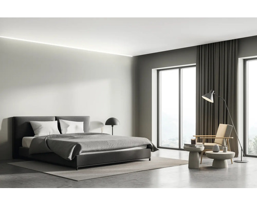 Helles Schlafzimmer mit Bett, Sessel, Tischlampe und Vorhängen