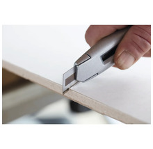 Ein Cuttermesser schneidet eine Platte.