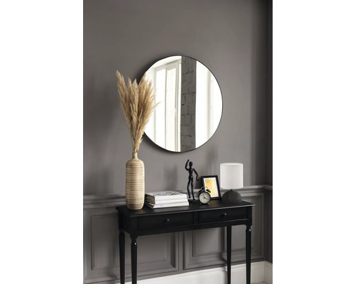 Dekoratives Interieur mit schwarzem Konsolentisch, rundem Spiegel, Lampe, Vase mit Pampasgras und weiteren Dekorationselementen