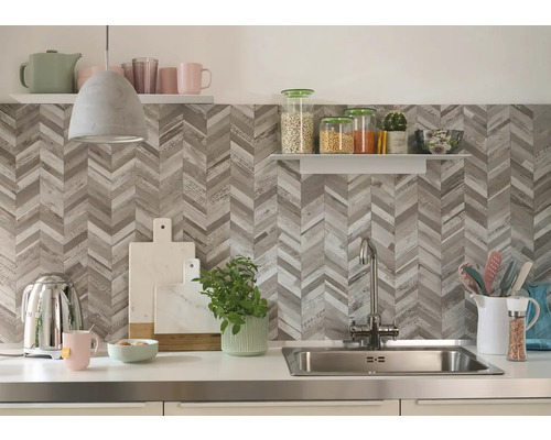 Küchenszene mit Spüle, Armatur, Küchenutensilien und Regalen vor einer Wand mit Fischgrätenmuster