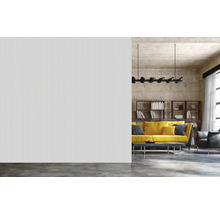 Innenaufnahme eines Wohnzimmers mit geriffelter Wand, Sofa, Bücherregal und Deckenleuchte