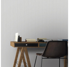 Büro mit Schreibtisch, Stuhl, Bücher und Schreibmaschine vor gestreifter Tapete