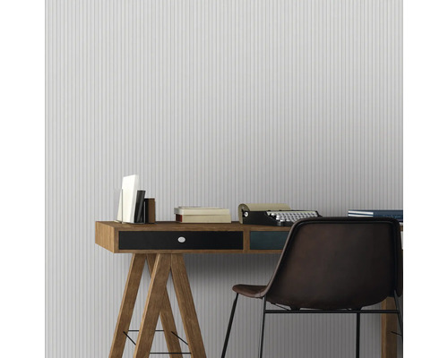 Büro mit Schreibtisch, Stuhl, Bücher und Schreibmaschine vor gestreifter Tapete