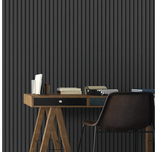 Szene mit Schreibtisch, Büchern, Schreibmaschine und Stuhl vor einer Wand mit Streifenmuster