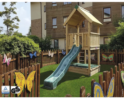 Holzspielhaus mit Rutsche auf Rasenfläche, umgeben von einem Zaun mit Schmetterlingsmotiven