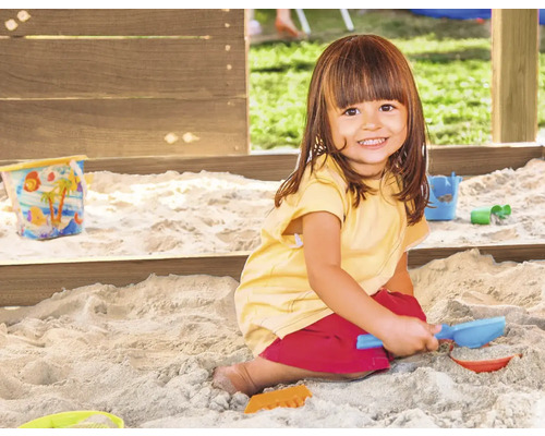 Mädchen spielt im Sandkasten mit Sandspielzeug