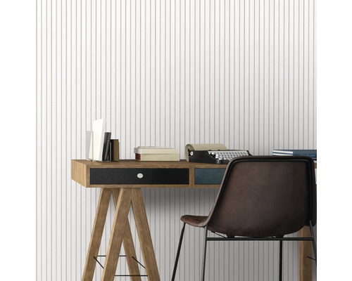 Arbeitszimmer mit Schreibtisch, Stuhl, Schreibmaschine und Büchern vor einer Tapete mit Streifenmuster