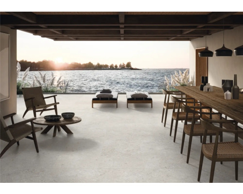 Terrasse mit Sitzmöbeln, Liegen und Esstisch mit Meerblick.