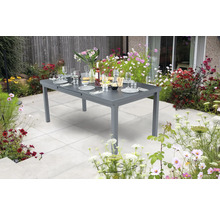 Gedeckter Gartentisch aus Metall in einem Garten mit Blumen