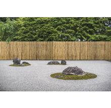 Zen-Garten mit Bambuszaun und Steinen auf Kies