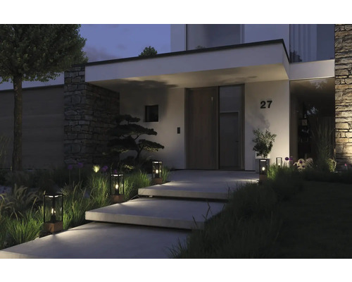 Beleuchteter Eingangsbereich eines Hauses mit Treppe und dekorativen Außenleuchten