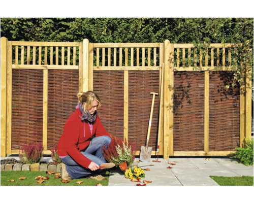 Gartenszene mit Holzzaun und Gärtnerin bei der Arbeit