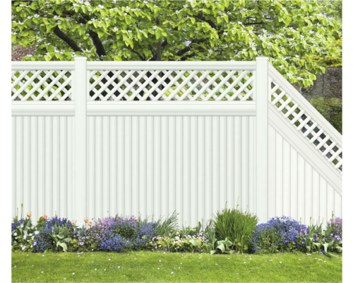 Weißer Gartenzaun mit Lattenmuster und Blumenbeet im Garten